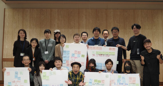 地域おこし協力隊の研修でホワイトボードを囲んで話し合う参加者と平野らすかる