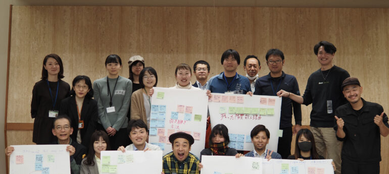 地域おこし協力隊の研修でホワイトボードを囲んで話し合う参加者と平野らすかる