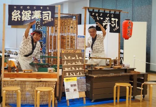 糸鋸寿司のカウンターに立つナルカリクラフトと平野らすかる